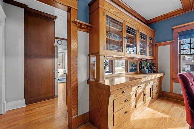 office area featuring light wood-style flooring, baseboards, and ornamental molding