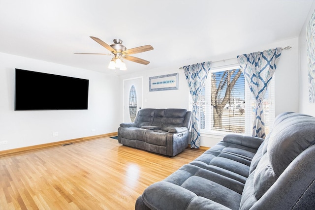 living area with a ceiling fan, wood finished floors, and baseboards