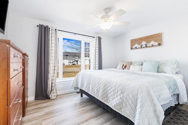 bedroom with light wood finished floors, baseboards, and a ceiling fan