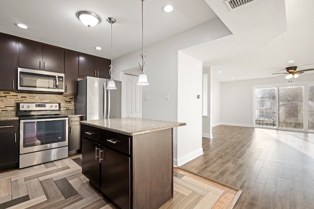 kitchen with light wood finished floors, stainless steel appliances, decorative backsplash, open floor plan, and a kitchen island