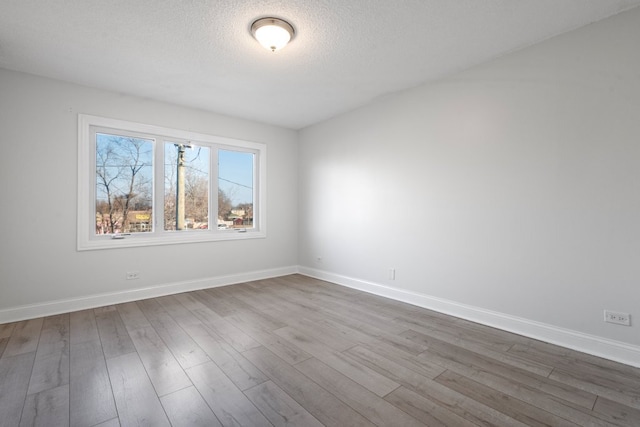 spare room with dark wood-style flooring, a textured ceiling, and baseboards