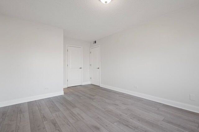 spare room featuring a textured ceiling, wood finished floors, and baseboards