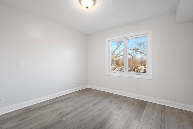 empty room featuring a textured ceiling, baseboards, and dark wood-type flooring