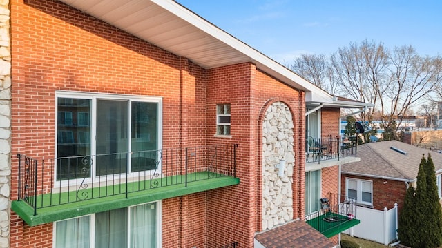 view of side of property with brick siding and a balcony