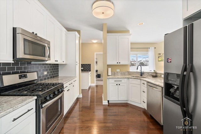 kitchen with a sink, stainless steel appliances, dark wood finished floors, and white cabinetry