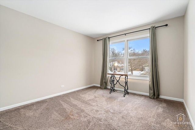 carpeted spare room featuring baseboards