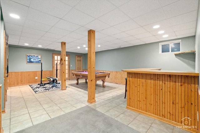 recreation room with a drop ceiling, a wainscoted wall, and wood walls