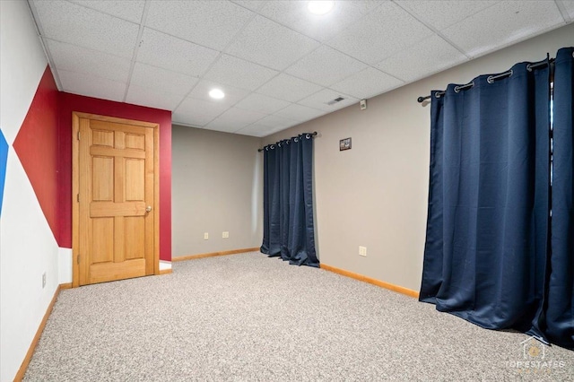 carpeted empty room with a drop ceiling and baseboards