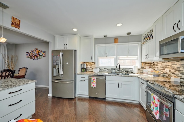 kitchen with dark wood-style floors, stainless steel appliances, backsplash, white cabinetry, and a sink