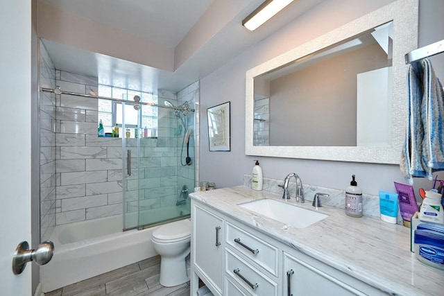 full bath with toilet, shower / bath combination with glass door, wood finish floors, and vanity