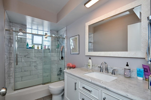 full bath with vanity, toilet, and bath / shower combo with glass door