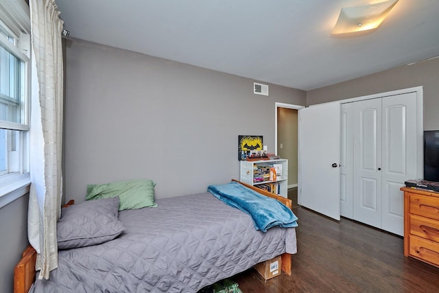 bedroom featuring dark wood-type flooring, a closet, and visible vents