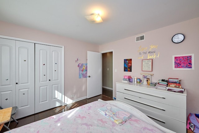 bedroom featuring baseboards, visible vents, a closet, and wood finished floors