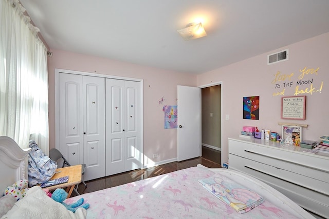 bedroom with baseboards, visible vents, a closet, and wood finished floors