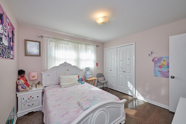 bedroom with dark wood-style flooring, a closet, and baseboards