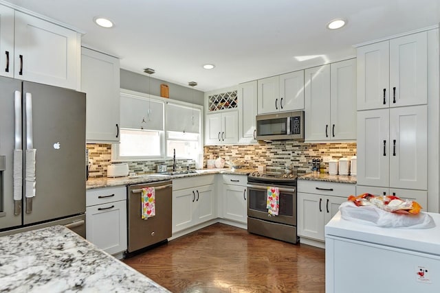 kitchen with tasteful backsplash, dark wood finished floors, stainless steel appliances, white cabinetry, and a sink