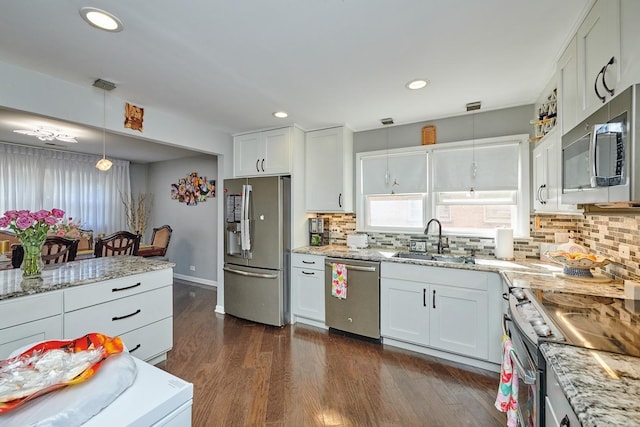 kitchen with dark wood-style flooring, pendant lighting, stainless steel appliances, a sink, and light stone countertops