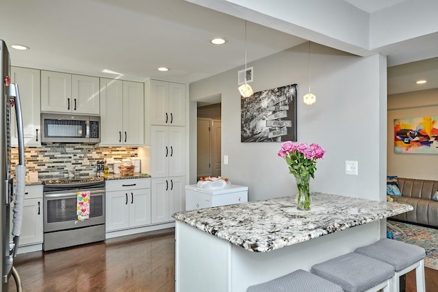 kitchen featuring visible vents, decorative backsplash, light stone counters, dark wood-style flooring, and stainless steel appliances