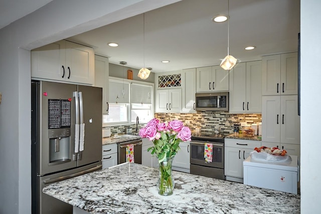 kitchen featuring pendant lighting, stainless steel appliances, light stone counters, and decorative backsplash