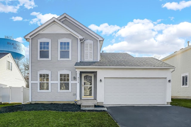 view of front of home featuring an attached garage, a shingled roof, a front lawn, fence, and driveway