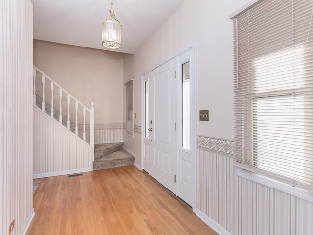 entryway featuring light wood-type flooring, visible vents, wainscoting, and stairway