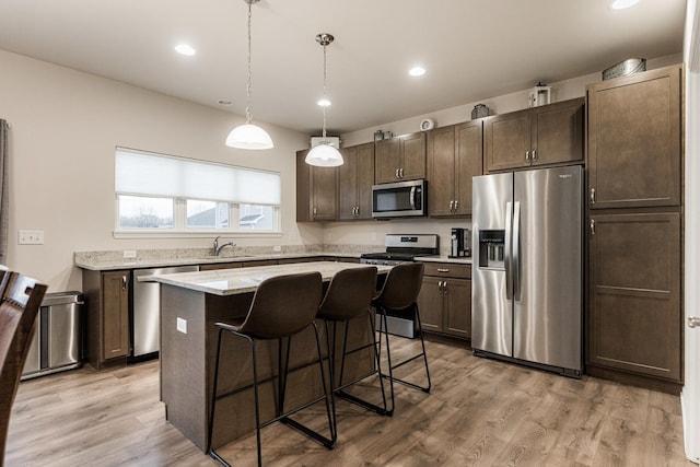 1125 Juniper Dr, Sycamore, IL 60178 - kitchen featuring appliances with stainless steel finishes, dark brown cabinets, a kitchen island, a breakfast bar, and light wood-type flooring