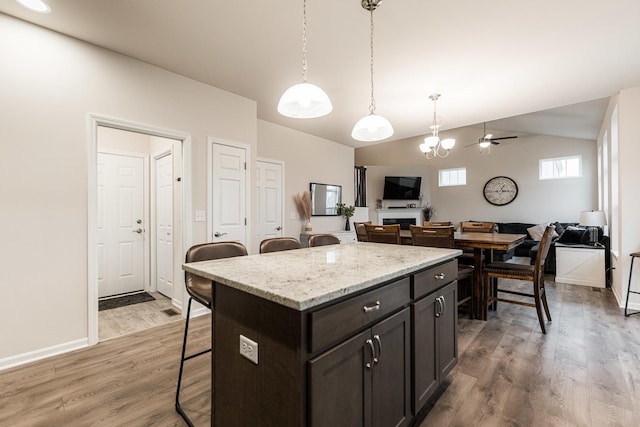 1125 Juniper Dr, Sycamore, IL 60178 - kitchen featuring a breakfast bar, open floor plan, lofted ceiling, wood finished floors, and decorative light fixtures