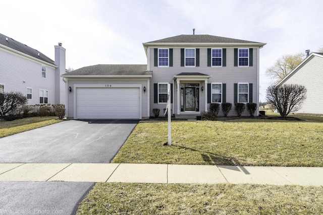 colonial house with a front lawn, an attached garage, and driveway