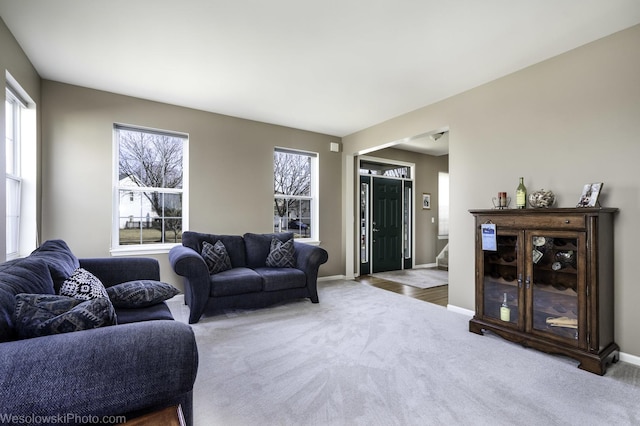 living area featuring baseboards, carpet floors, and stairs