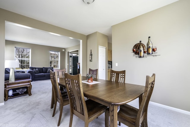 dining area with baseboards and light colored carpet