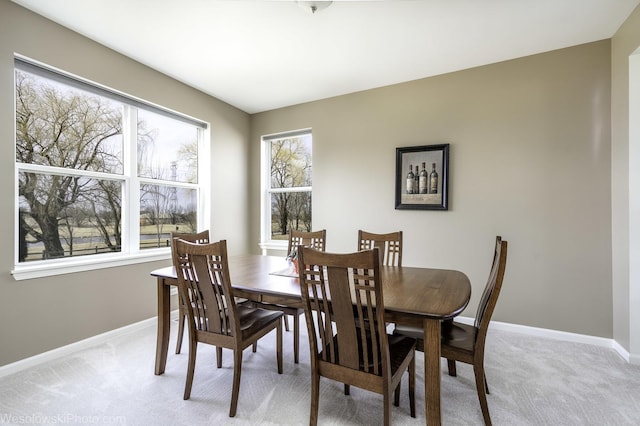 dining area with baseboards and light colored carpet