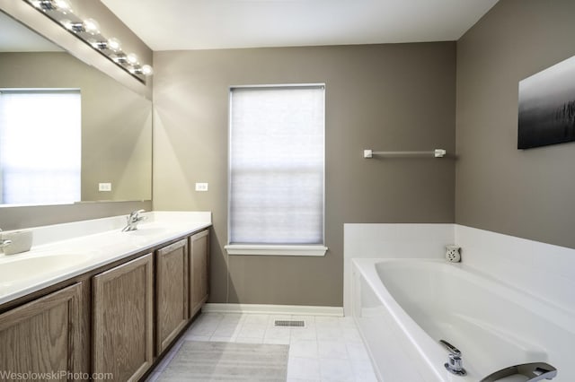 full bath with tile patterned floors, plenty of natural light, a bath, and a sink