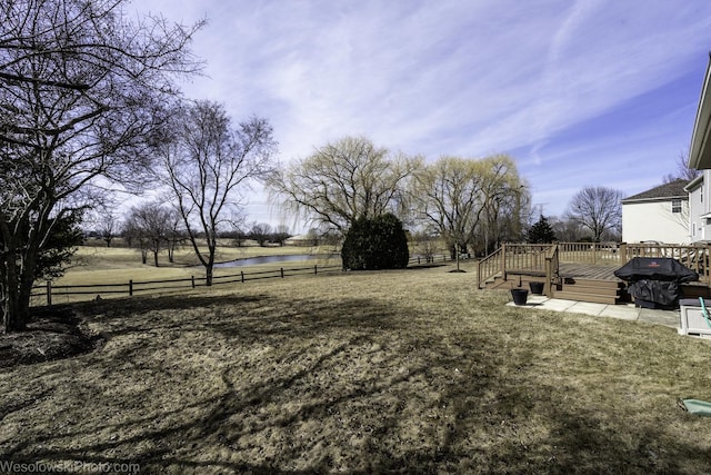 view of yard featuring a deck with water view and fence