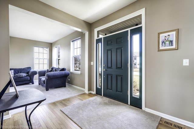 foyer entrance featuring visible vents, wood-type flooring, and baseboards