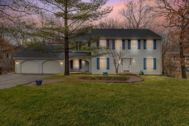 colonial home with driveway, a yard, and an attached garage