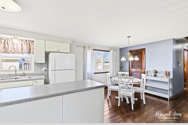 kitchen with freestanding refrigerator, dark wood-style flooring, a sink, and backsplash