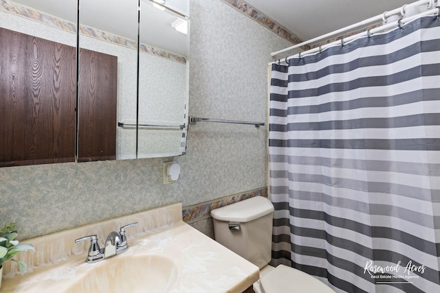 bathroom with a shower with curtain, vanity, toilet, and wallpapered walls