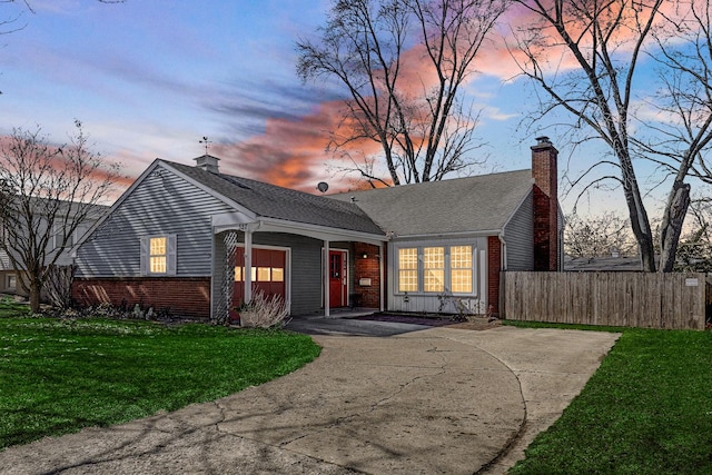 view of front of home with a garage, a chimney, fence, a yard, and brick siding