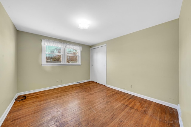 unfurnished bedroom with a closet, baseboards, and hardwood / wood-style floors