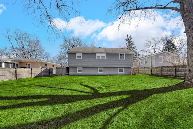 back of property with a chimney, a fenced backyard, and a lawn