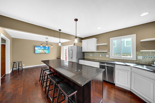 kitchen with open shelves, appliances with stainless steel finishes, a breakfast bar area, and backsplash