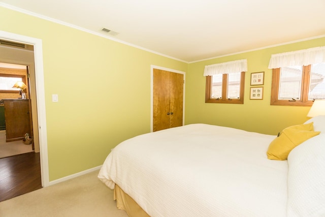 carpeted bedroom featuring a closet, visible vents, crown molding, and baseboards