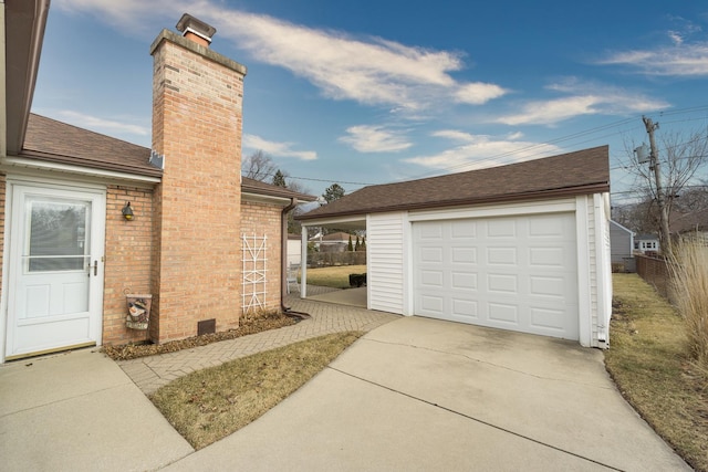 view of home's exterior featuring brick siding, a chimney, concrete driveway, and an outdoor structure