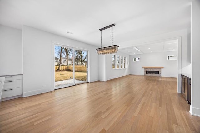 unfurnished living room featuring baseboards, a fireplace, visible vents, and light wood-style floors