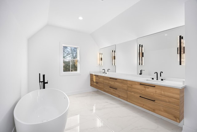 bathroom with a freestanding tub, a sink, vaulted ceiling, marble finish floor, and double vanity