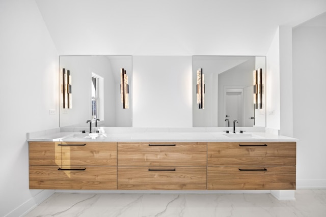 full bathroom with marble finish floor, double vanity, a sink, and baseboards