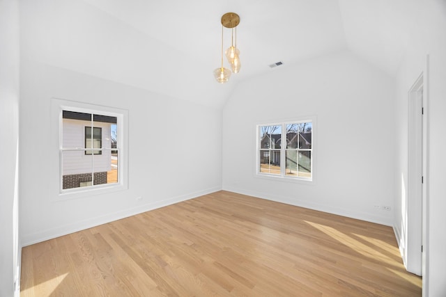 unfurnished room with light wood-type flooring, lofted ceiling, visible vents, and baseboards