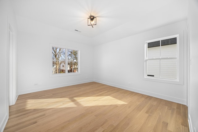 spare room featuring light wood-style flooring, visible vents, and baseboards