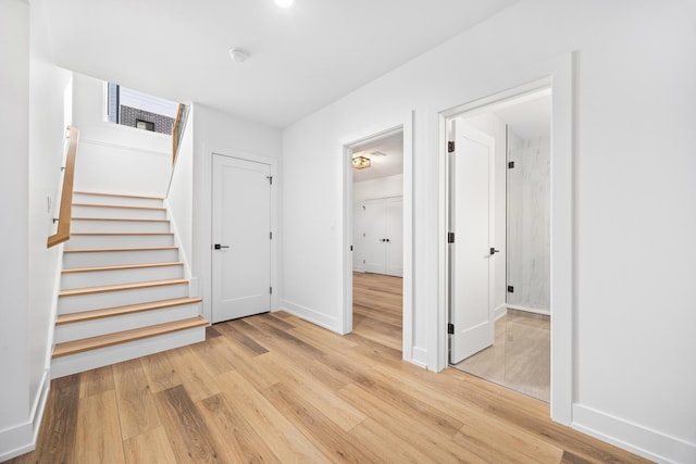 interior space with light wood-style flooring, stairs, and baseboards