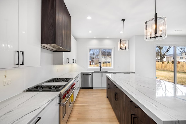 kitchen with wall chimney exhaust hood, modern cabinets, stainless steel appliances, and a sink